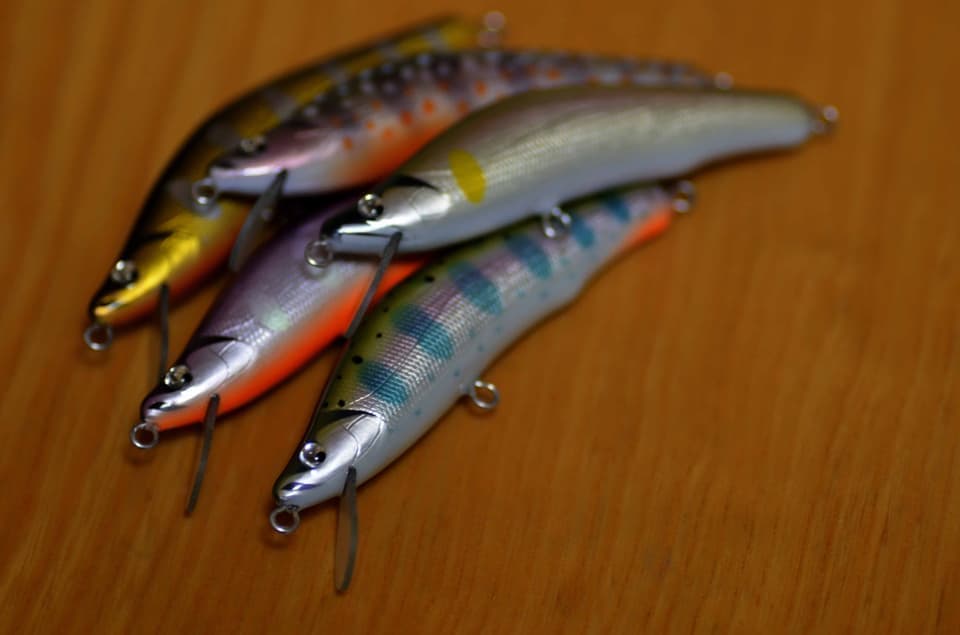茶色い木の机に並べられた腹オレのルアー