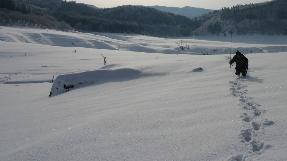 雪の中をラッセルして進む釣り人
