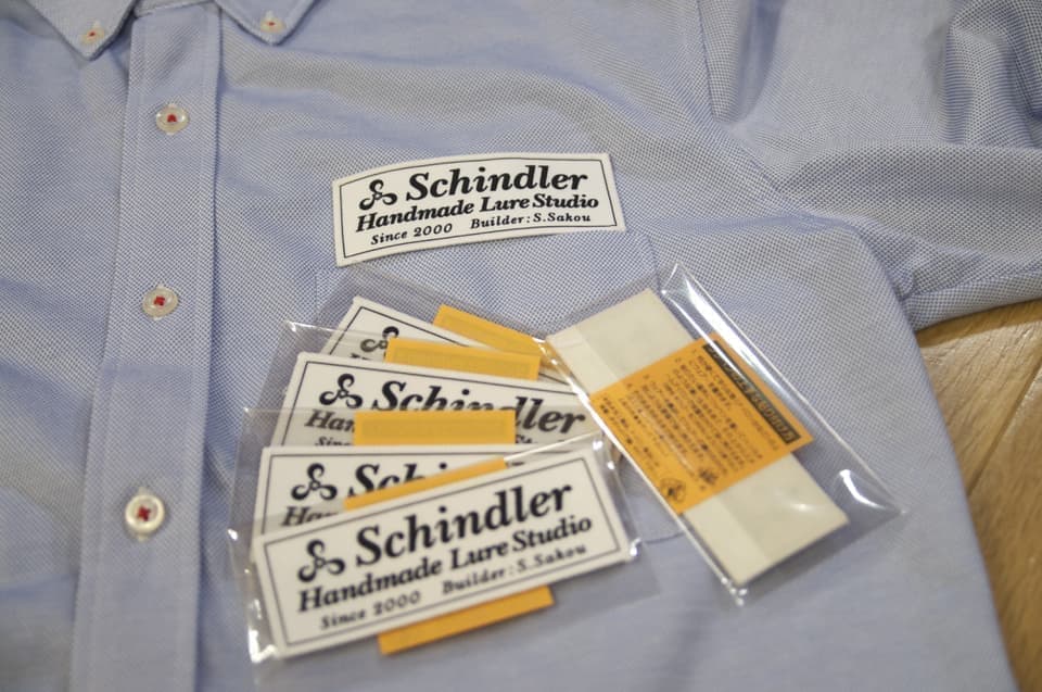 ブルーのシャツに貼られたワッペンと袋入り製品